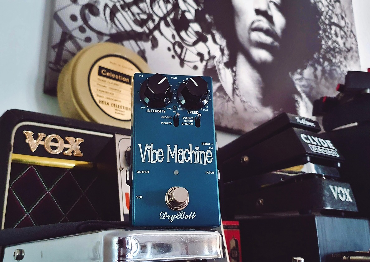 DryBell Vibe Machine V-3 guitar pedal with various gear, including wah pedals and a small VOX amp.