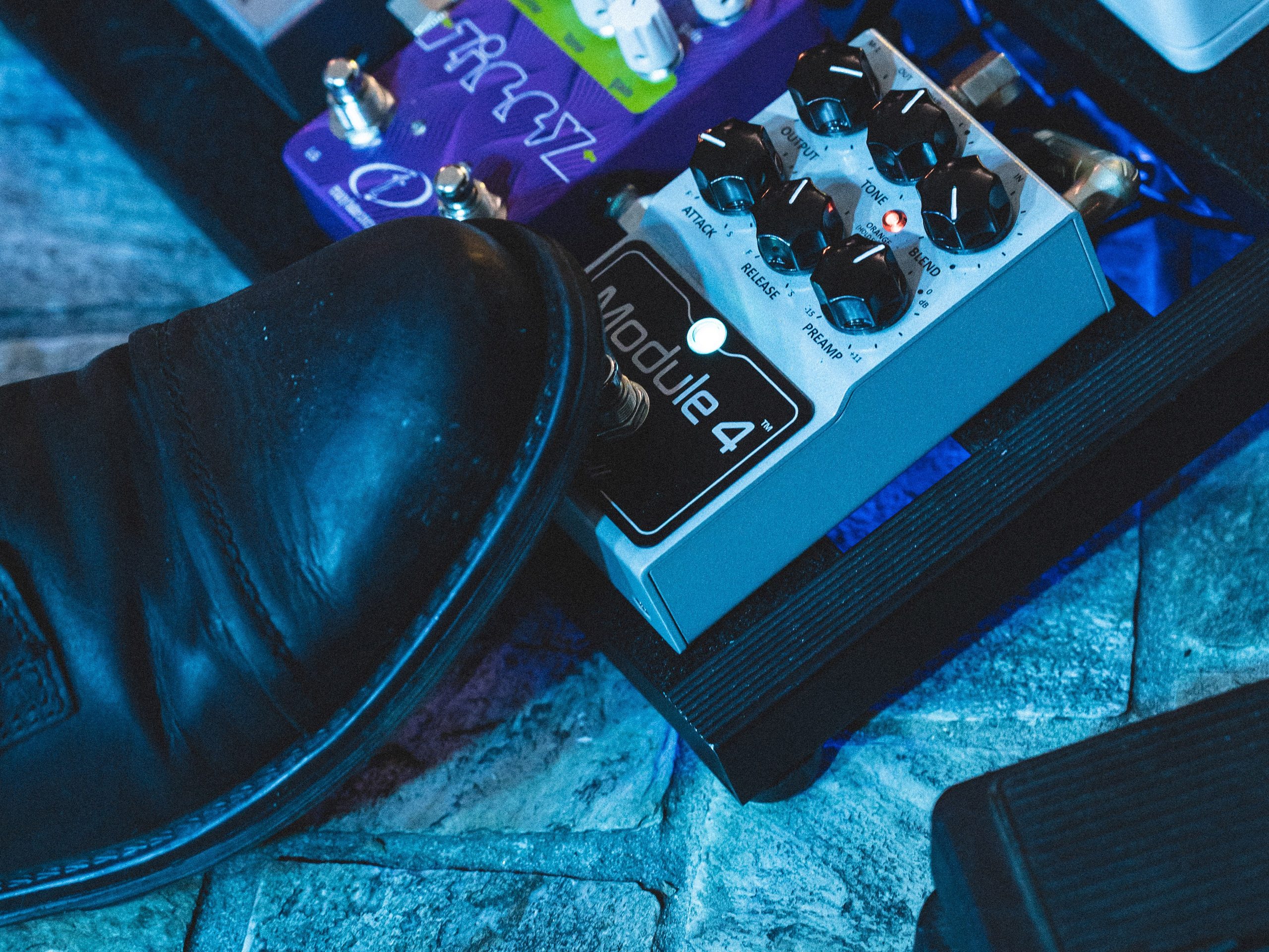 DryBell Module 4 guitar pedal on a pedalboard, with Kiki Golub's foot pressing the pedal on stage.